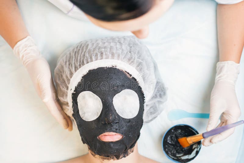 Fachowa kobieta, cosmetologist w zdroju salonie stosuje borowinową twarzy maskę zdjęcie royalty free Fachowa kobieta, cosmetologist w zdroju salonie stosuje borowinową twarzy maskę zdjęcie royalty free