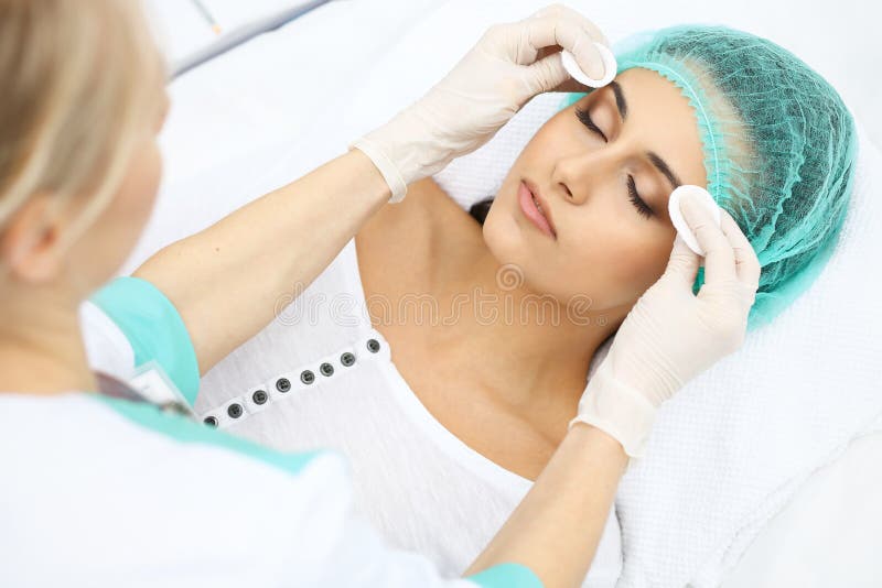 Fachowy beautician i młoda kobieta w piękno salonie Makeup artysty dotyka klienta skóra z bawełnianymi ochraniaczami, closeu zdjęcie royalty free Fachowy beautician i młoda kobieta w piękno salonie Makeup artysty dotyka klienta skóra z bawełnianymi ochraniaczami, closeu zdjęcie royalty free