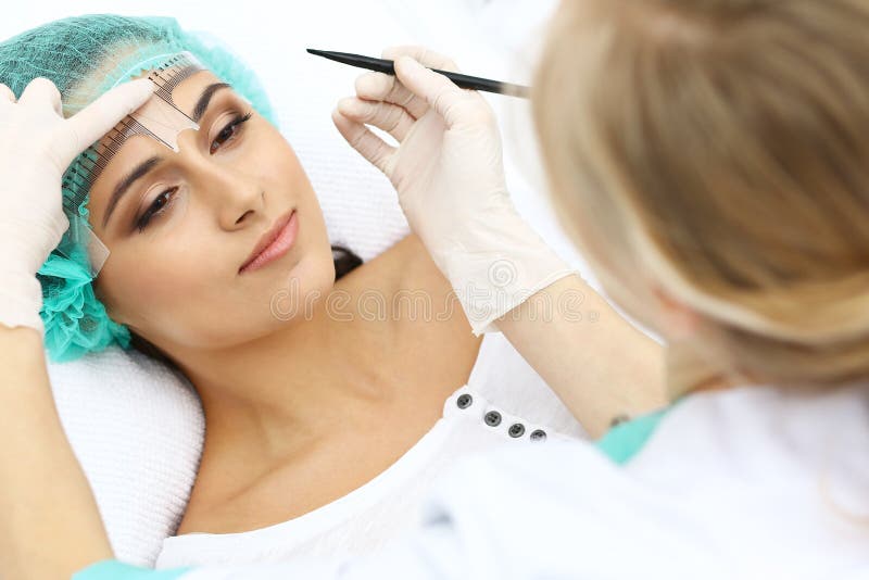 Fachowy beautician iść korygować brwi linię przy kobiety twarzą używać kosmetycznej władcy Stały brwi makeup wewnątrz zdjęcia royalty free Fachowy beautician iść korygować brwi linię przy kobiety twarzą używać kosmetycznej władcy Stały brwi makeup wewnątrz zdjęcia royalty free