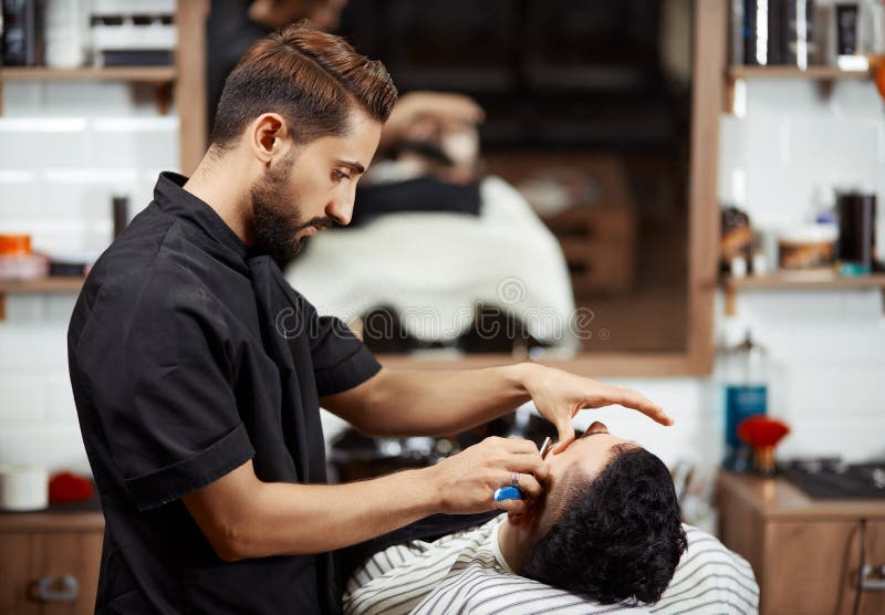 Fachowy hairstylist w czarnej czułości i tnący chleb dla mężczyzna zdjęcie stock Fachowy hairstylist w czarnej czułości i tnący chleb dla mężczyzna zdjęcie stock