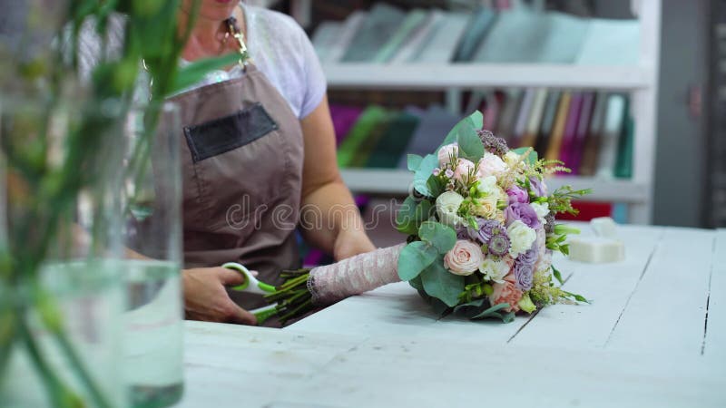 Fachowy kwiaciarni ułożenie z tasiemkowego kwiatu ślubnym bukietem w kwiecistego projekta studiu