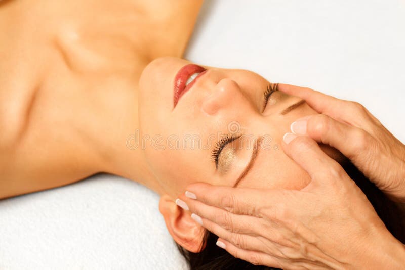 Woman gets facial massage, closeup, on bright background