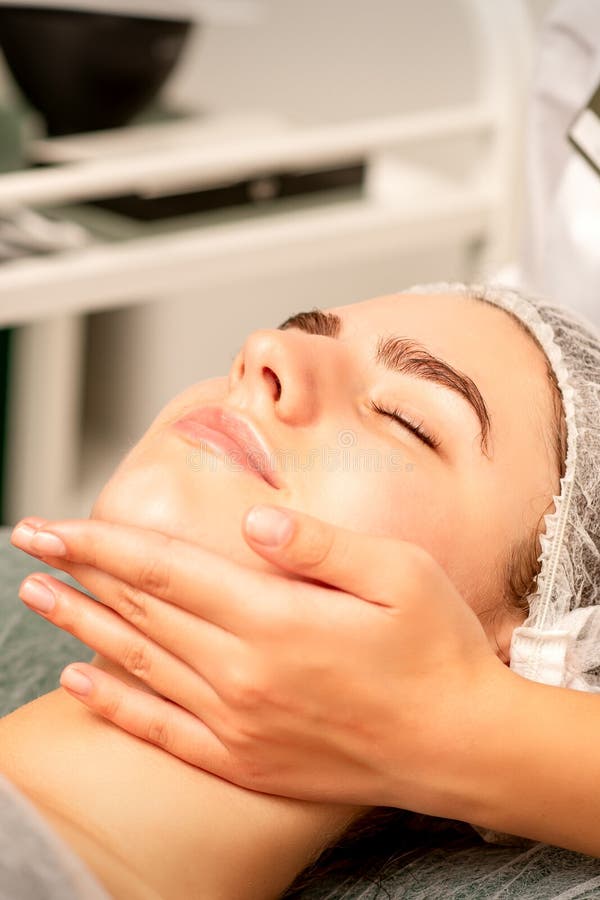 Facial Massage Hands Of A Masseur Massaging Neck Of A Young Caucasian Woman In A Spa Salon The