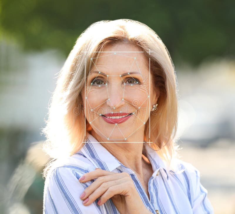 Facial recognition system. Mature woman with scanner frame and digital biometric grid, outdoors