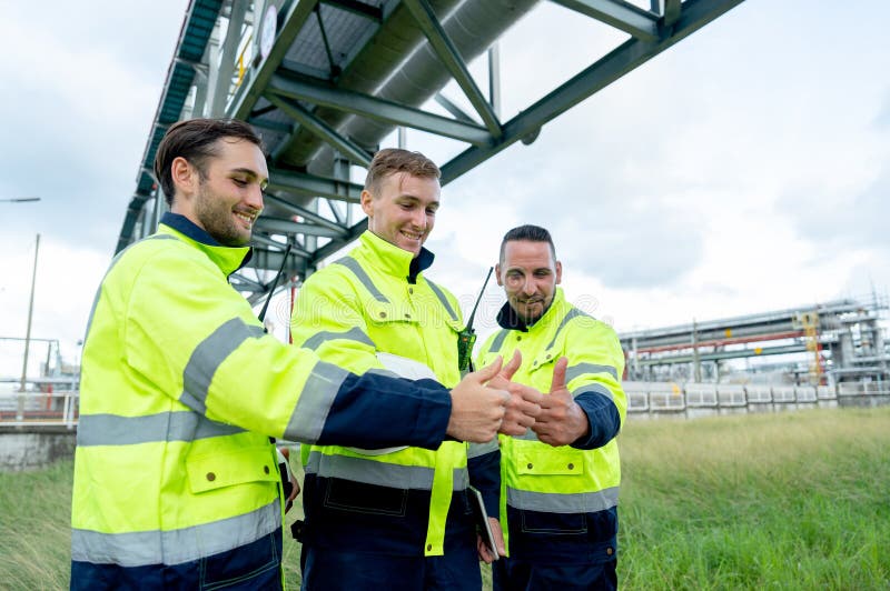 Factory engineer or technician workers stand with show thumbs up together stay under petrochemical pipeline with day light stock photo