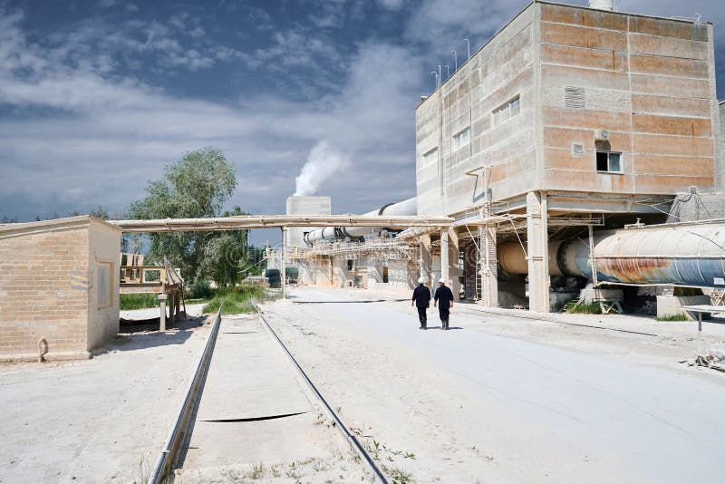 Large factory of gas silica blocks bricks and calx production under cloudy sky. Workers walk along manufacturing industrial complex open territory