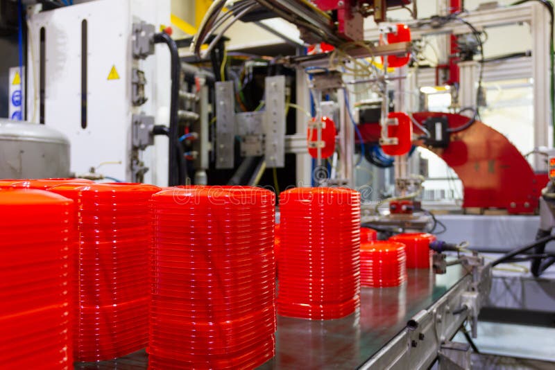 Factory machine placing red plastic lids on conveyor belt royalty free stock images