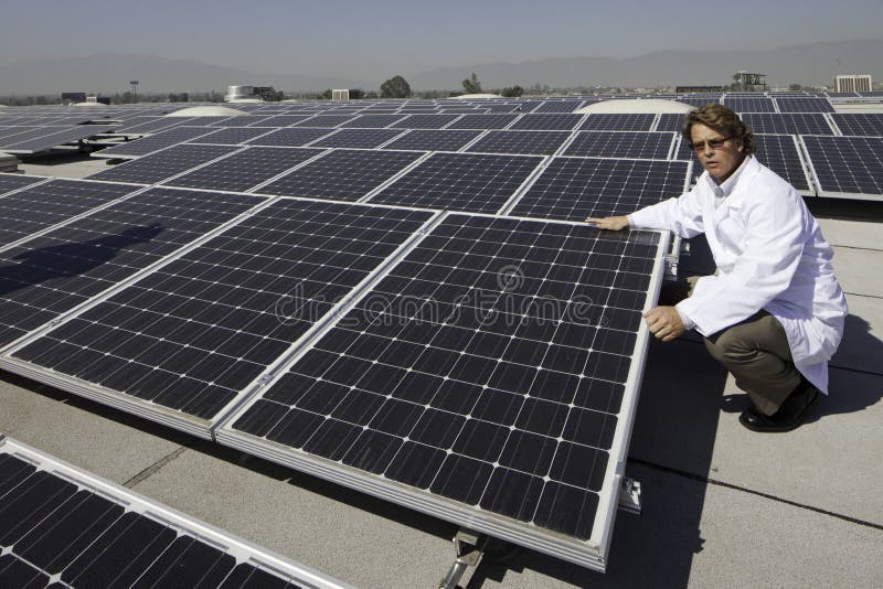 Factory worker sitting besides solar panels