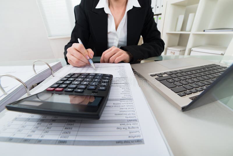 Close-up Of Businesswoman Calculating Invoice With Calculator. Close-up Of Businesswoman Calculating Invoice With Calculator