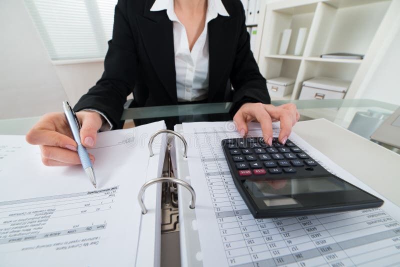 Close-up Of Businesswoman Calculating Invoice With Calculator. Close-up Of Businesswoman Calculating Invoice With Calculator