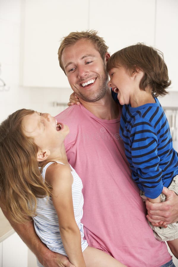 Fader hemmastadda Giving Children Cuddle royaltyfria bilder Fader hemmastadda Giving Children Cuddle royaltyfria bilder