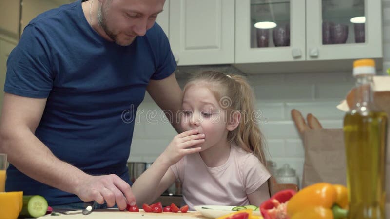 Fader lär sin dotter om vikten av hälsosamma livsmedel i köket arkivfilmer