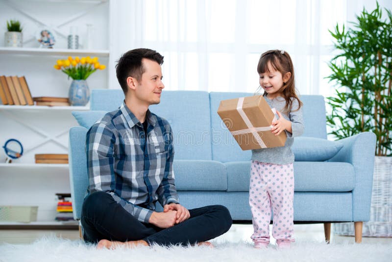 Fader och dotter eller syskongrupp med en gåva i inre av rummet Faders begrepp för ferie för dag, barns dag royaltyfri foto Fader och dotter eller syskongrupp med en gåva i inre av rummet Faders begrepp för ferie för dag, barns dag royaltyfri foto