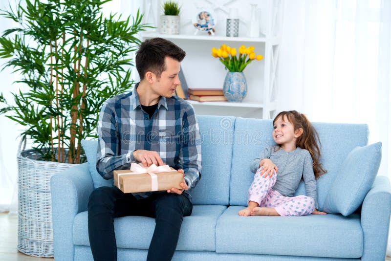 Fader och dotter eller syskongrupp med en gåva i inre av rummet Faders begrepp för ferie för dag, barns dag royaltyfri fotografi Fader och dotter eller syskongrupp med en gåva i inre av rummet Faders begrepp för ferie för dag, barns dag royaltyfri fotografi