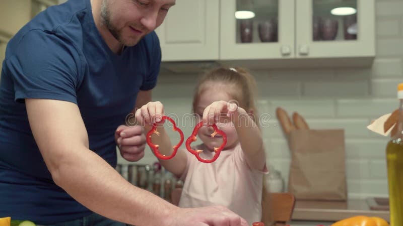 Fader och dotter förbereder en hälsosam frukost medan de leker med grönsaker i köket lager videofilmer