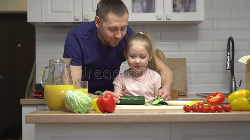 Fader och dotter kokar ihop medan de smakar färska grönsaker arkivfilmer