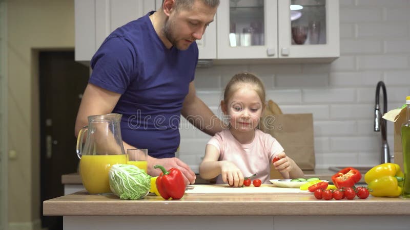Fader och dotter som bereder frisk sallad i köket stock video