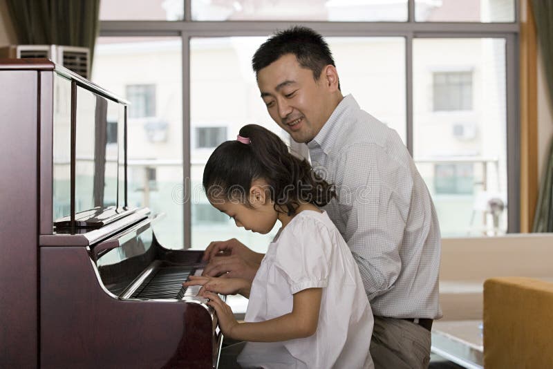Fader och dotter som spelar pianot royaltyfri foto Fader och dotter som spelar pianot royaltyfri foto
