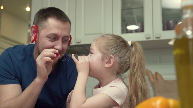 Fader och dotter som ställer upp för kameran med grönsaker som skapar kreativa bilder stock video
