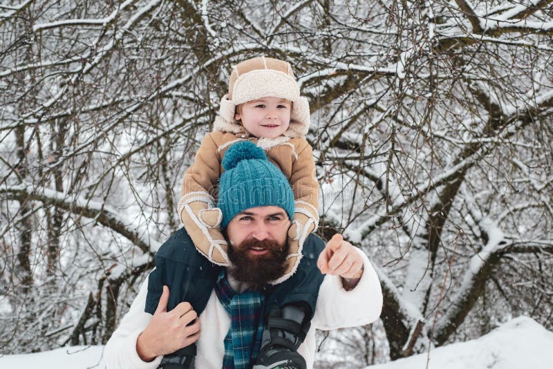 Fader som ger son skjuts tillbaka i parken Cute son kramar sin pappa på vintersemester Bästa vinterspel för lyckliga familjer royaltyfri fotografi