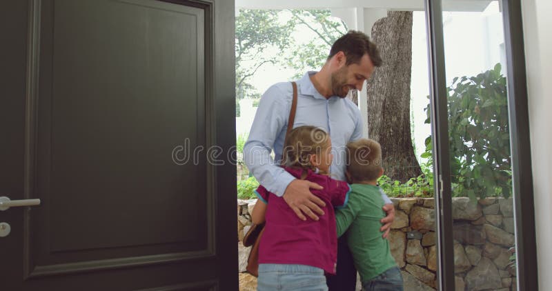 Fader som omfamnar hans barn på dörren i ett bekvämt hem 4k