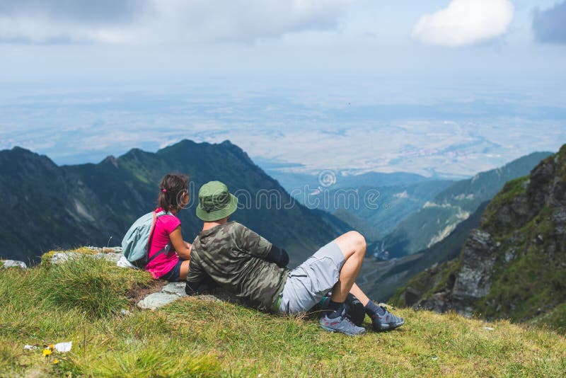 Fadern med sin lilla flicka vilande på en bergspets och beundrar landskapet