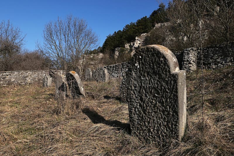 Vybledlé náhrobky kolem kamenné zdi židovského hřbitova