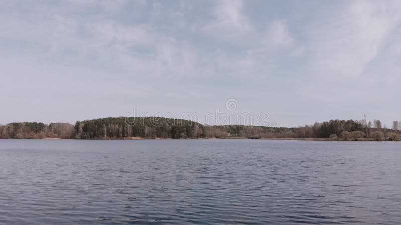 Faible vol de caméra entre les arbres sur la rive et au-dessus de la surface de l'eau du lac. clips vidéos