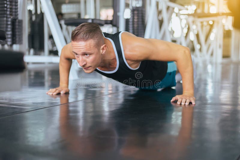 Faire actif d'homme fort soulèvent et des exercices sur le plancher au gymnase images stock Faire actif d'homme fort soulèvent et des exercices sur le plancher au gymnase images stock