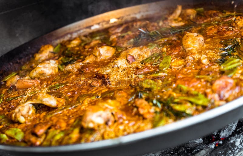 Faisant cuire et faisant une Paella espagnole traditionnelle au-dessus du feu ouvert photos stock Faisant cuire et faisant une Paella espagnole traditionnelle au-dessus du feu ouvert photos stock