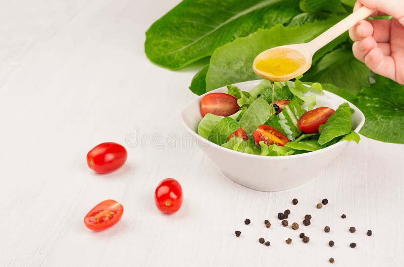 Faisant cuire la salade fraîche de ressort des verts, les tranches de tomate-cerise sur le fond en bois blanc, copient l'espace L photos libres de droits Faisant cuire la salade fraîche de ressort des verts, les tranches de tomate-cerise sur le fond en bois blanc, copient l'espace L photos libres de droits