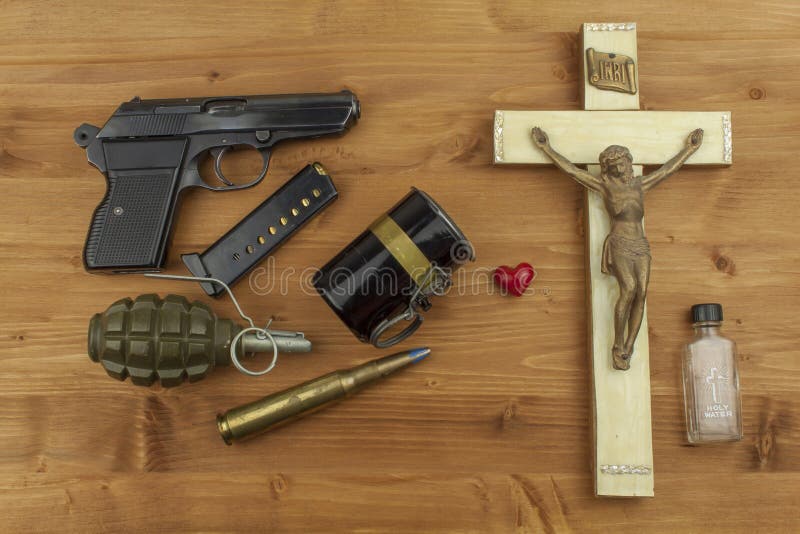 Faith against violence. A wooden crucifix with the lettering INRI and guns. stock photography Faith against violence. A wooden crucifix with the lettering INRI and guns. stock photography