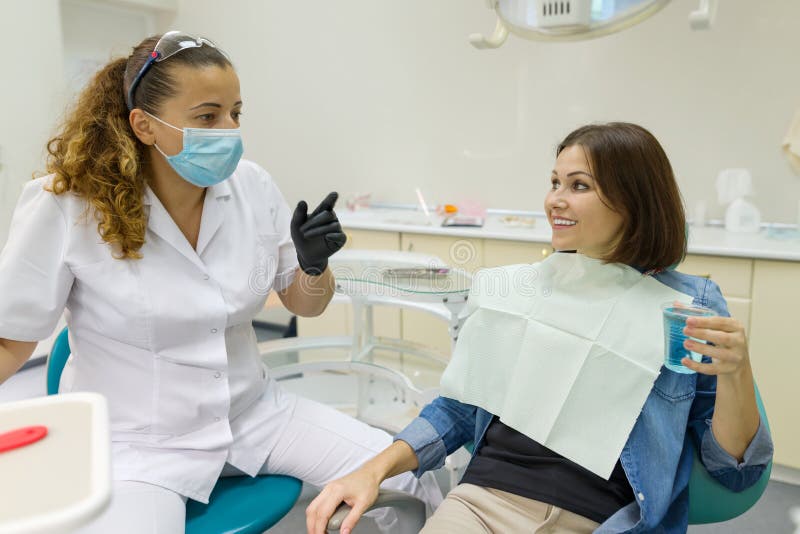 Fala paciente fêmea a um dentista no escritório dental Conceito da medicina, da odontologia e dos cuidados médicos imagem de stock Fala paciente fêmea a um dentista no escritório dental Conceito da medicina, da odontologia e dos cuidados médicos imagem de stock