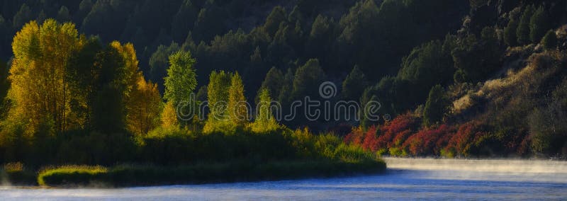 Fall Autumn Trees with River or Lake Water and Forest Stock Photo