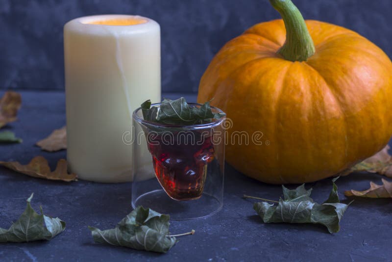 Fall Halloween pumpkins, candle, glass in the form of a skull on a dark background stock image Fall Halloween pumpkins, candle, glass in the form of a skull on a dark background stock image