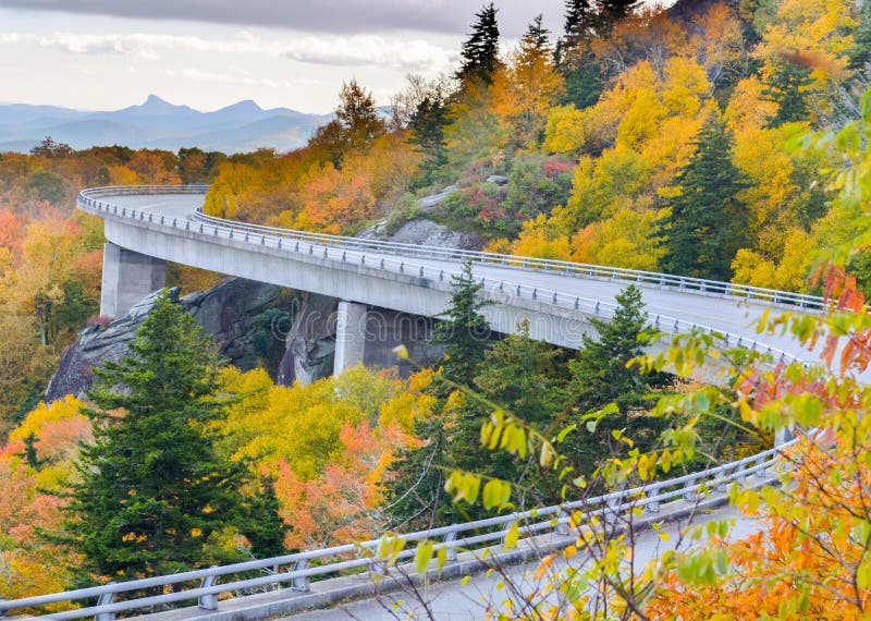 Fall at Lynn Cove viaduct, at grandfather Mountain on the Blue Ridge Pkwy. A bridge in the sky, a bridge that goes around grandfather Mountain to protect a giant boulder field. In North Carolina. Fall colors red yellows and brown greens with the bridge making a huge S weaving its way around the mountain. Horizontal Photo photograph