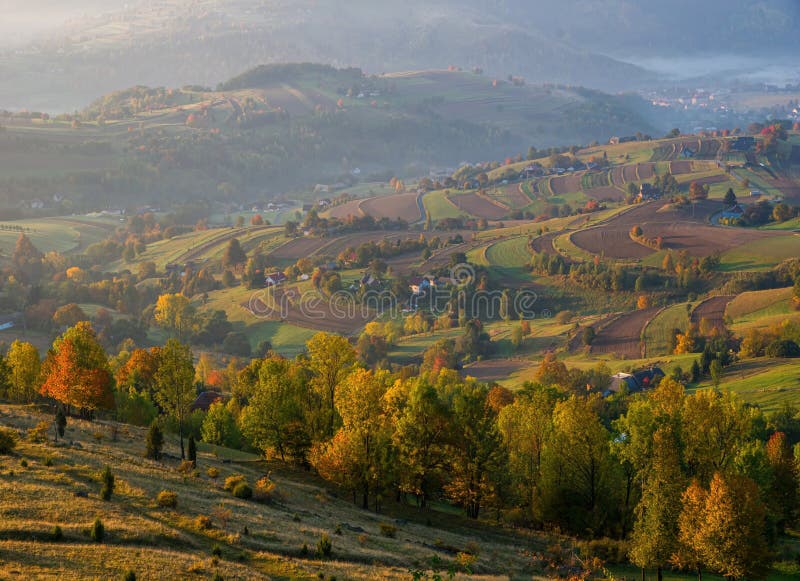 Jeseň na Slovensku. Krajina lúk a polí pri Hriňovej. Jesenné farebné stromy pri východe slnka.
