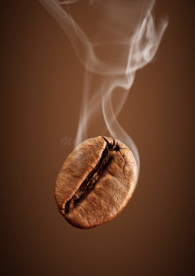 Fallende Kaffeebohne der Nahaufnahme mit Rauche auf braunem Hintergrund