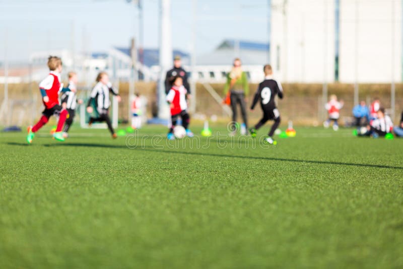 Blur of young kids playing a soccer training match outdoors on an artificial soccer pitch. Blur of young kids playing a soccer training match outdoors on an artificial soccer pitch.