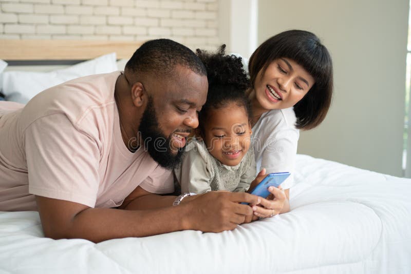 Rapaz sério jogando jogo online no celular, seus dois pais sentados perto  dele e olhando para a tela. família em casa e conceito de comunicação