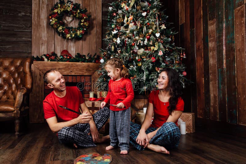 A Família Nos Pijamas Joga Ao Lado De Uma árvore De Natal E De Uma Chaminé  Foto de Stock - Imagem de lareira, interior: 104185068