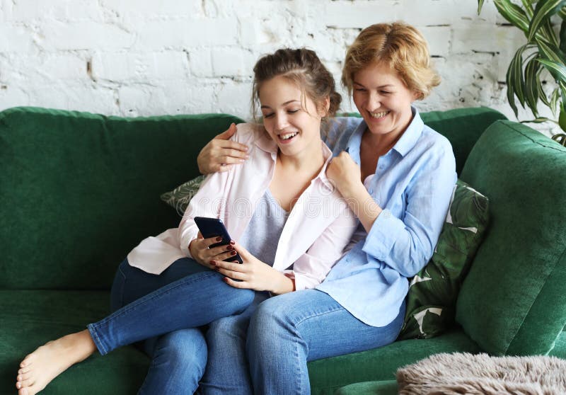 Fam?lia, povos e tecnologia Mulher envelhecida e sua filha adulta que usa o smartphone em casa imagem de stock royalty free Fam?lia, povos e tecnologia Mulher envelhecida e sua filha adulta que usa o smartphone em casa imagem de stock royalty free