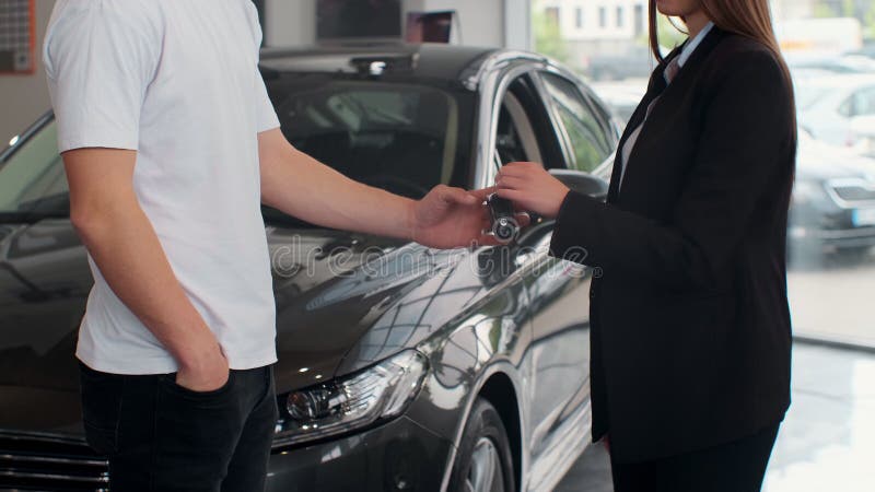 Famale hand gives a car keys to male hand in the car dealership close up. Unrecognized auto seller and a woman who royalty free stock image Famale hand gives a car keys to male hand in the car dealership close up. Unrecognized auto seller and a woman who royalty free stock image