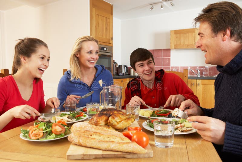 Famiglia adolescente che mangia insieme pranzo nella cucina fotografie stock