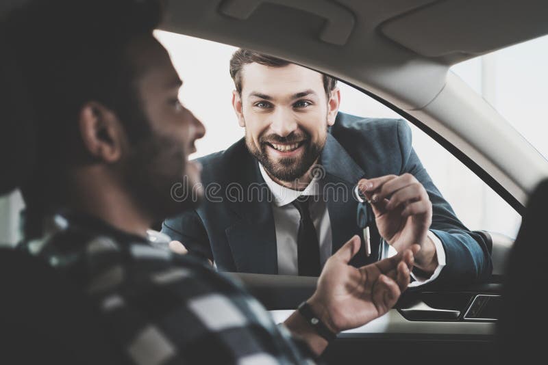 Famiglia afroamericana al concessionario auto Il rappresentante sta fornendo le chiavi per la nuova automobile fotografie stock