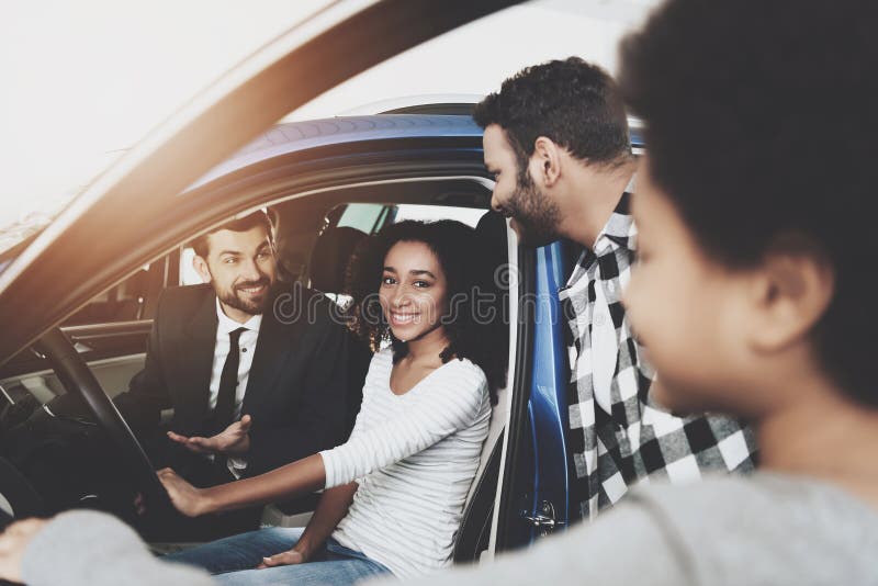 Famiglia afroamericana al concessionario auto Il rappresentante sta mostrando la nuova automobile alla madre fotografia stock libera da diritti