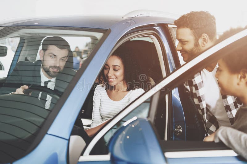 Famiglia afroamericana al concessionario auto Il rappresentante sta mostrando la nuova automobile alla madre fotografie stock libere da diritti