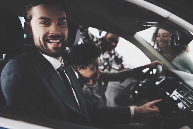 Famiglia afroamericana al concessionario auto Il rappresentante sta mostrando la nuova automobile al ragazzo fotografia stock