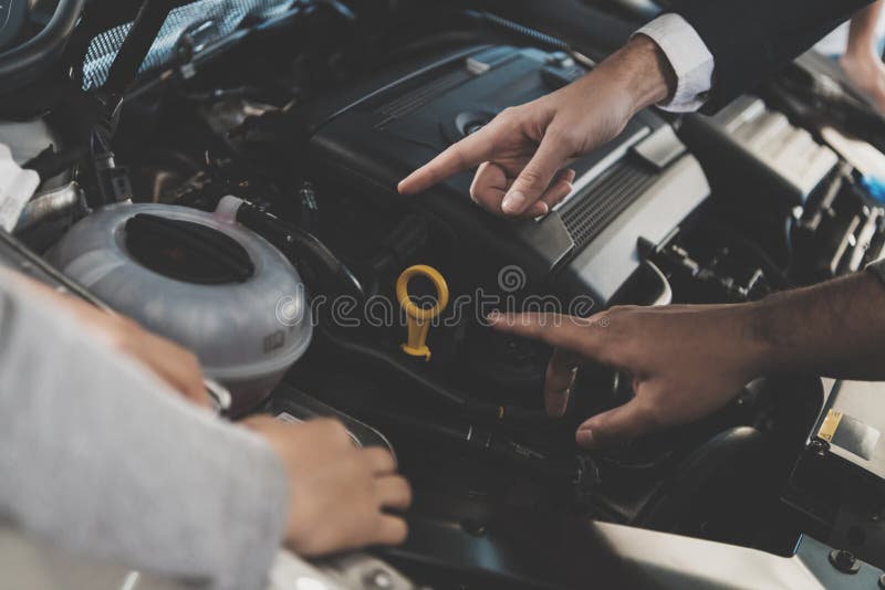Famiglia afroamericana al concessionario auto Il rappresentante sta mostrando il motore di nuova automobile fotografia stock libera da diritti