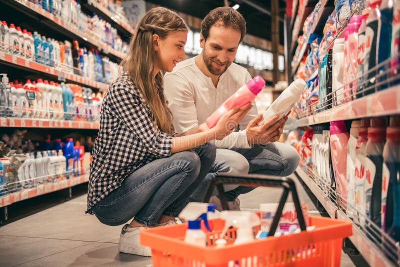 Handsome dad and his pretty daughter are choosing household objects while doing shopping in supermarket. Handsome dad and his pretty daughter are choosing household objects while doing shopping in supermarket